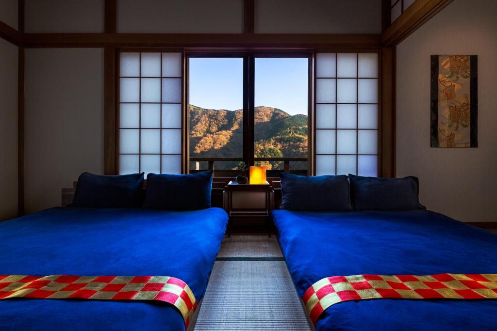 two beds in a room with a view of a mountain at Taisho Modern Villa Zen in Hakone