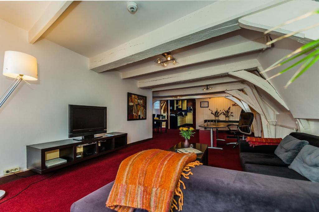 een woonkamer met een bank en een tv bij Hotel de Vischpoorte, hartje Deventer en aan de IJssel in Deventer