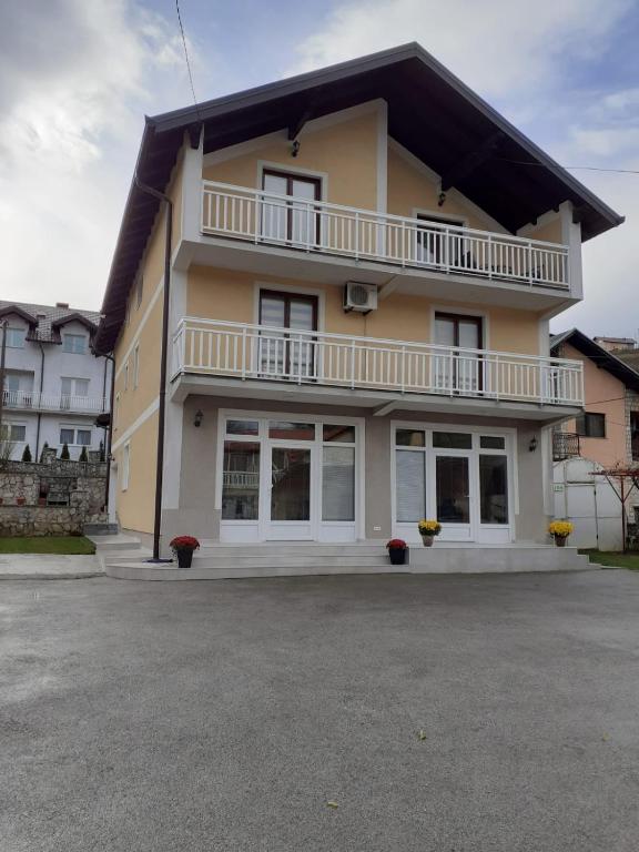 a large yellow building with a balcony at Sweet Holiday Home in Hadžići