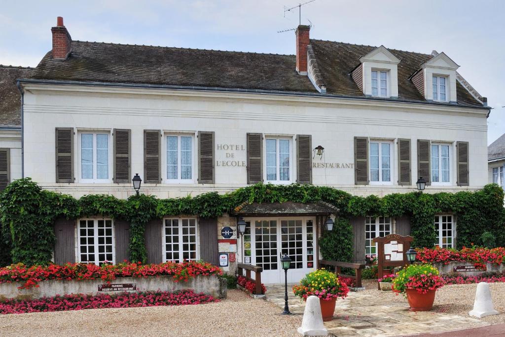 a white building with flowers in front of it at Logis Hôtel Auberge De L'ecole in Pontlevoy