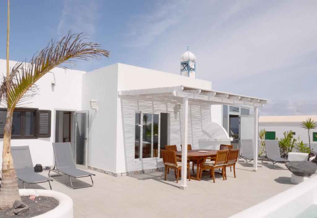 a patio with a wooden table and chairs at Villa Tranquilidad with amazing private terrace and heated pool in Charco del Palo