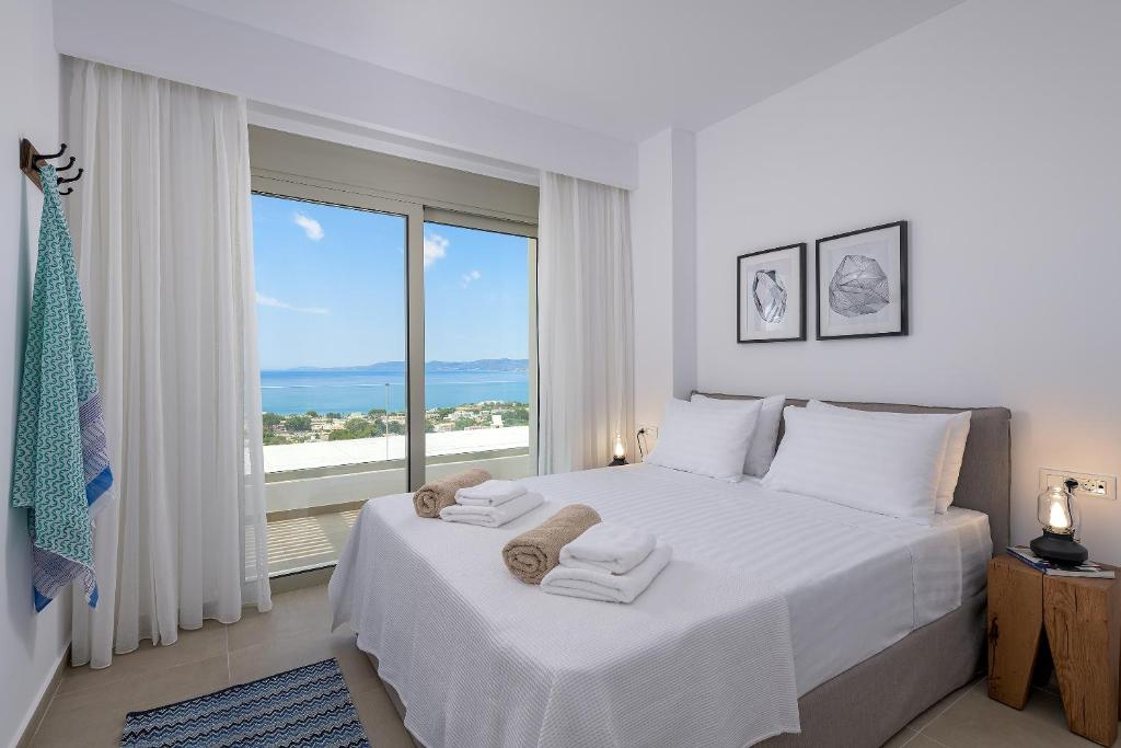 sypialnia z dużym białym łóżkiem i dużym oknem w obiekcie Villa Mimosa in Pefkos (Lindos area) w Líndos