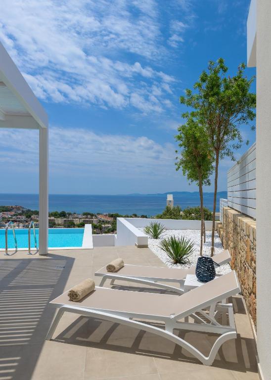 patio z białym stołem i widokiem na ocean w obiekcie Villa Mimosa in Pefkos (Lindos area) w Líndos