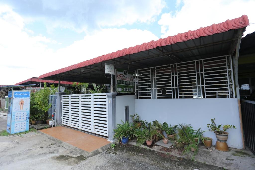 a white building with wooden shutters and potted plants at Singgahan Keluarga Jitu in Jitra