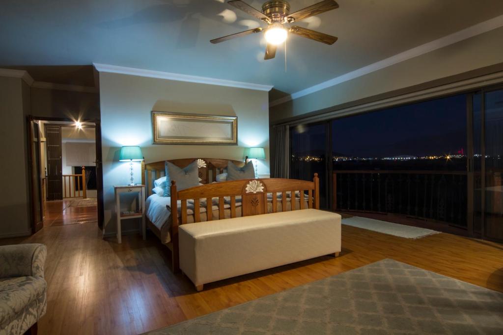 a bedroom with a bed with a ceiling fan and a balcony at Casa Mia Guesthouse in Table View