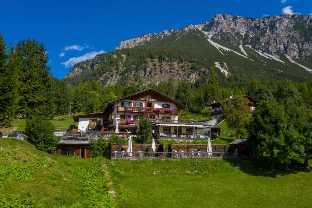 a house on a hill in front of a mountain at Baita Fraina in Cortina dʼAmpezzo