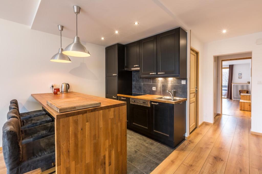a kitchen with black cabinets and a wooden counter top at Apartment Periades in Chamonix-Mont-Blanc