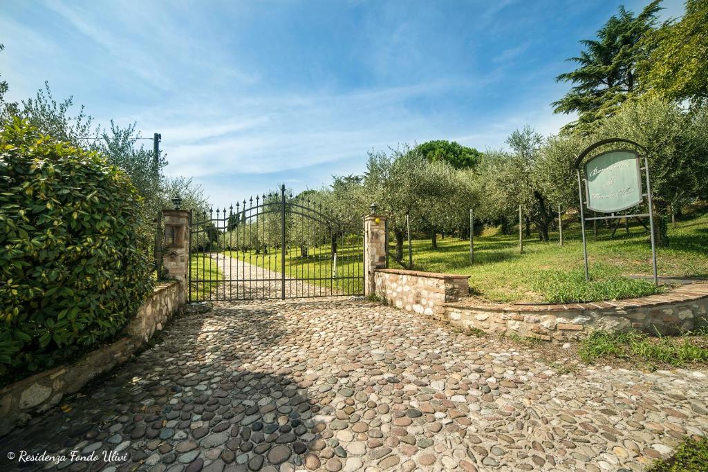 un cancello per un giardino con passerella in pietra di Residenza Fondo Ulivi a Ponti Sul Mincio