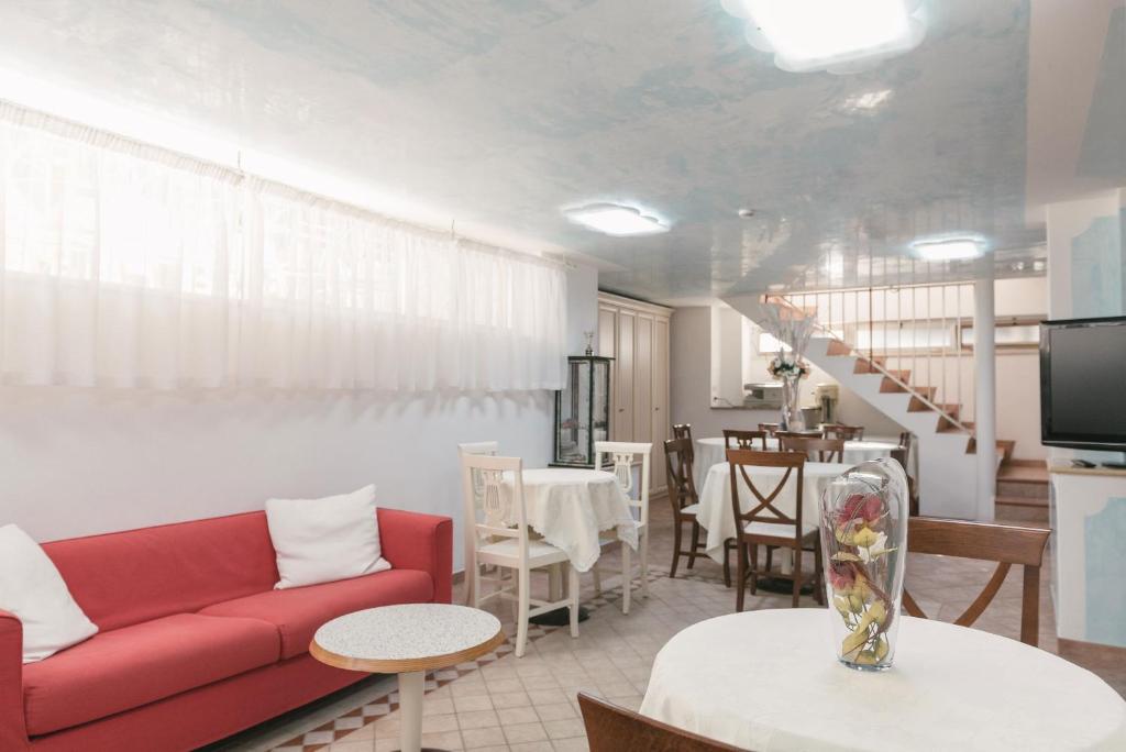 salon z czerwoną kanapą i stołem w obiekcie Hotel Altair w mieście Misano Adriatico