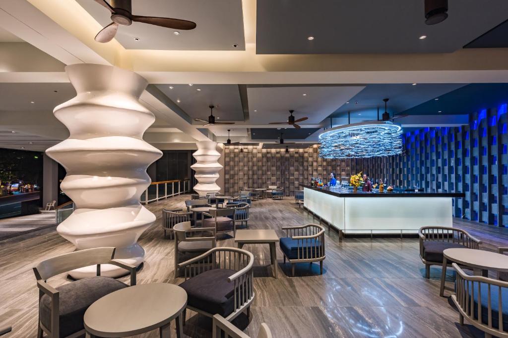 a lobby with tables and chairs and a bar at Oceanfront Beach Resort - SHA Extra Plus in Patong Beach