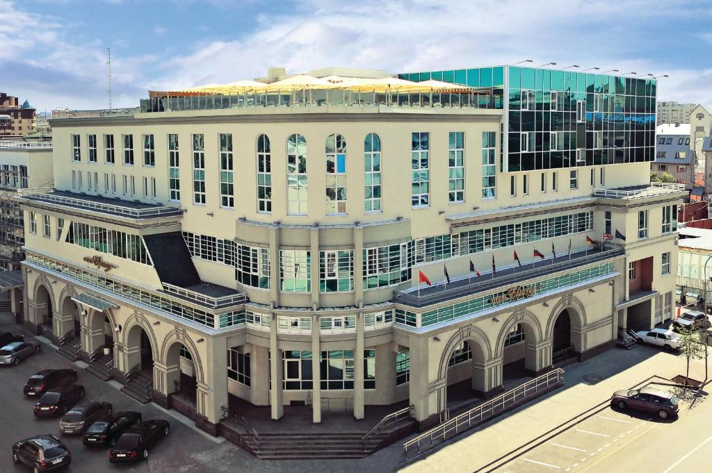 un gran edificio blanco con coches estacionados frente a él en Eurasia Business Hotel Tyumen, en Tyumen