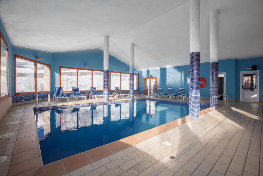 una gran piscina con sillas y paredes azules en Wuau! Apartamentos Solana de Ransol, en Ransol