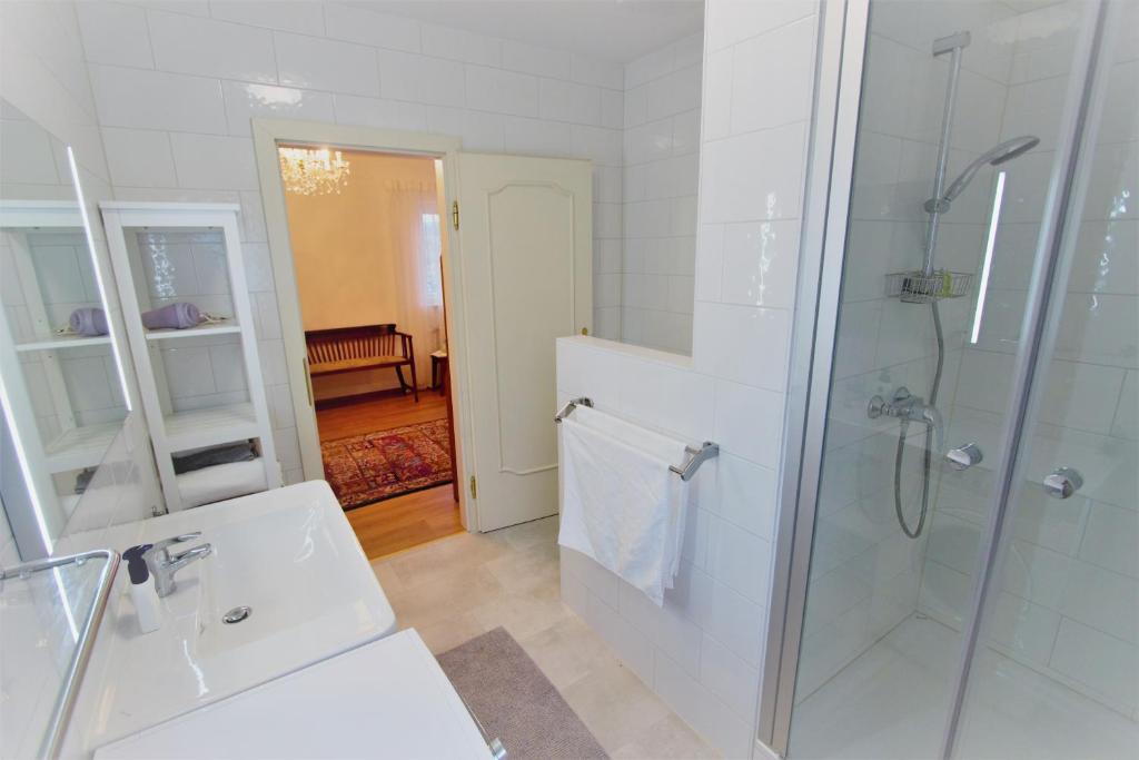 een witte badkamer met douche en wastafel bij Christl - Apartment mit Garten und Pool zur Mitbenutzung in Wenen