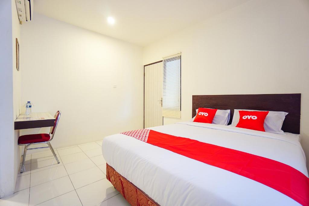 um quarto com uma cama com almofadas vermelhas e uma secretária em OYO 1838 COZY Home em Manado