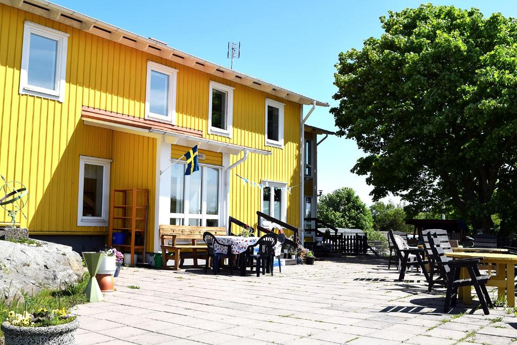 un bâtiment jaune avec des tables et des chaises devant lui dans l'établissement Solhem Bohus Björkö, à Björkö