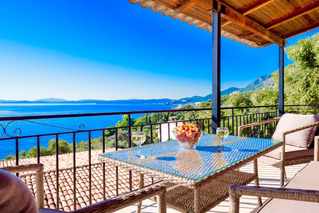 a table on a balcony with a view of the ocean at Nissaki Suite Poseidon by Sealand Villas in Nisakion