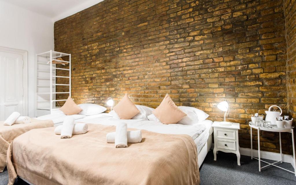 two beds in a room with a brick wall at Downtown Bratislava B&B in Bratislava