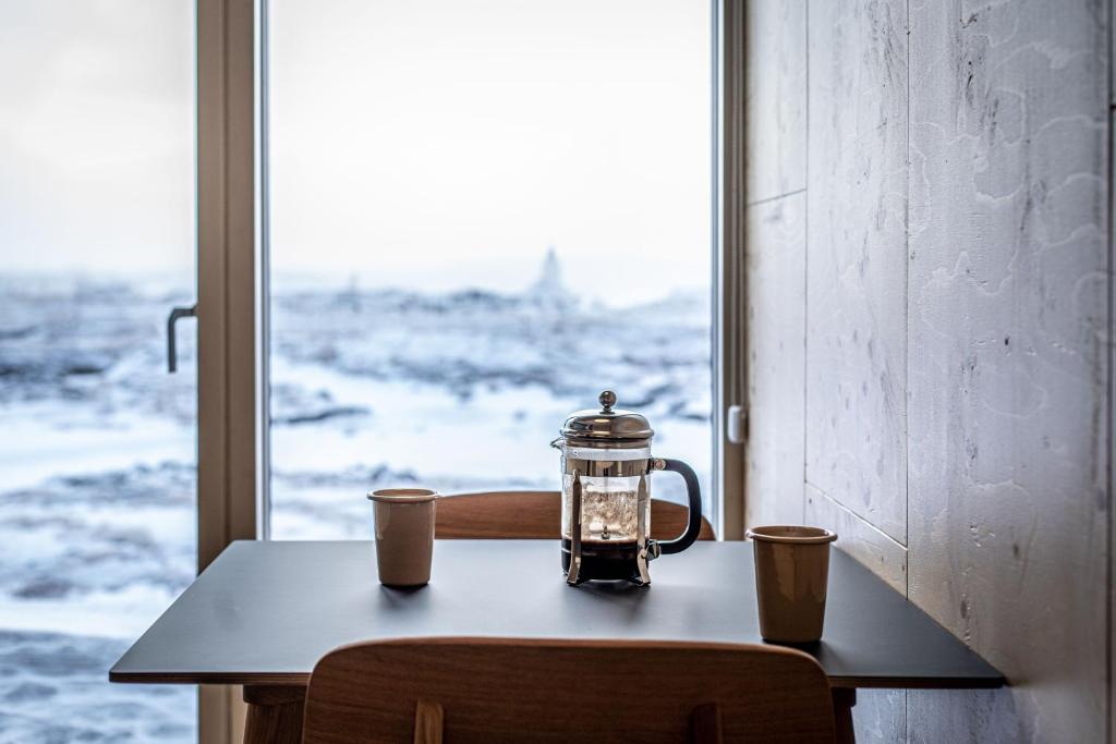 a tea kettle on a table in front of a window at Aska, Modern Cabin in Myvatn