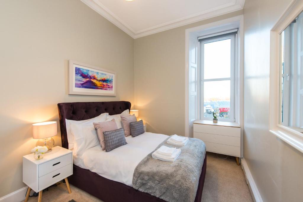 a bedroom with a bed and two windows at The Polwarth Apartment in Edinburgh