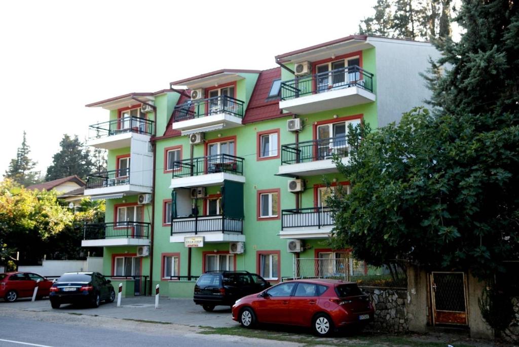 un edificio verde con macchine parcheggiate di fronte di Apartments Villa Zora a Star Dojran