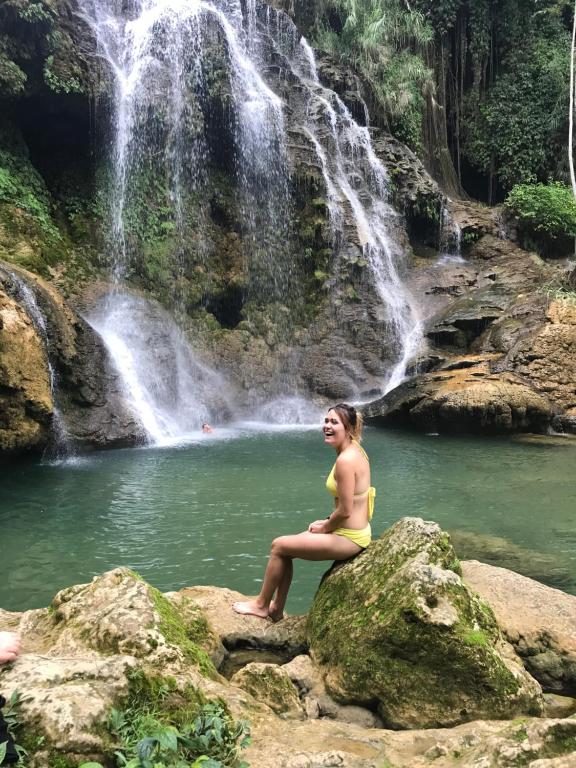 Una donna seduta su una roccia di fronte a una cascata di LePont Mu Waterfall Bungalow a Hòa Bình
