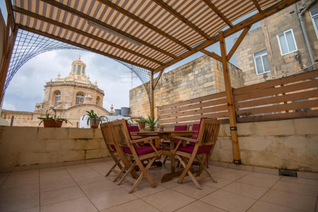 a wooden table and chairs on a patio with a building at Valletta Grand Central in Valletta