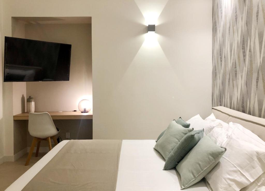 um quarto com uma cama branca e almofadas verdes em LAUS Teatro Petruzzelli Suite em Bari
