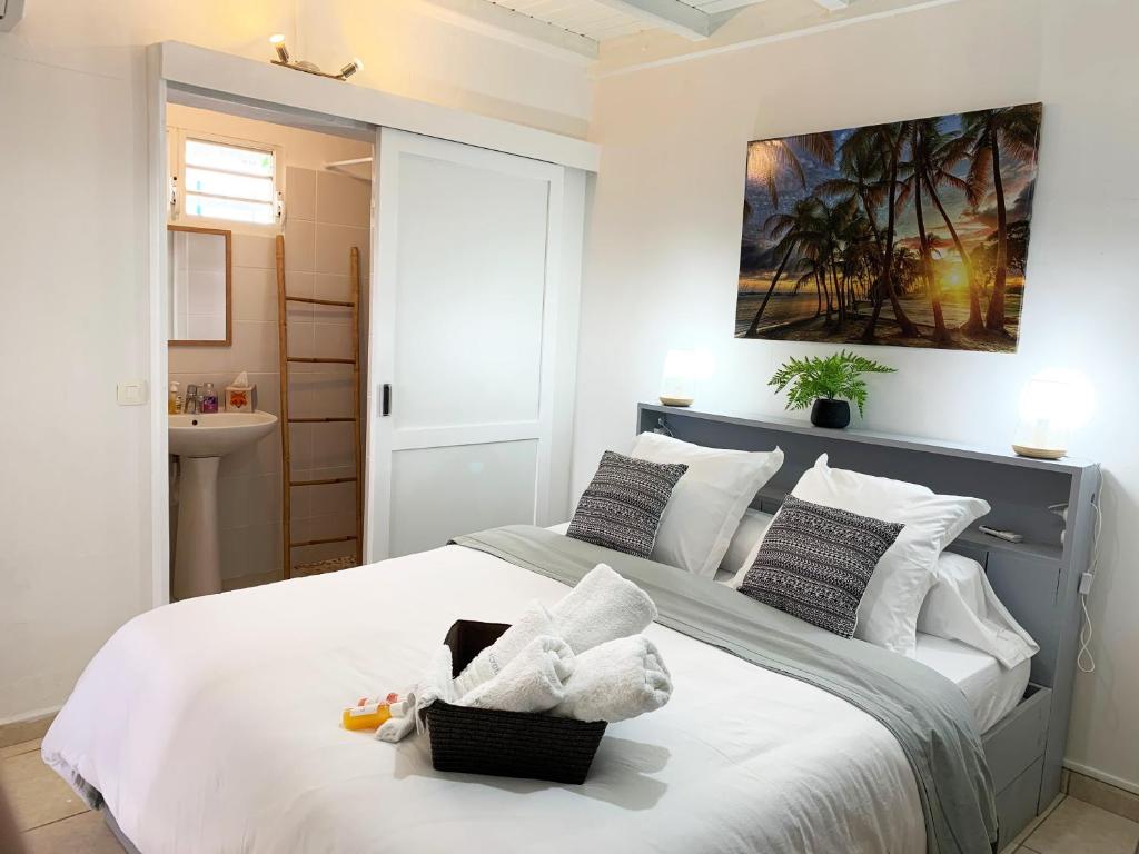 um quarto com uma cama grande e almofadas brancas em Le MABOUYA em Petit-Bourg