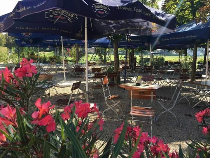 a patio with tables and chairs with umbrellas and flowers at Gasthaus Pension Hörner in Moos