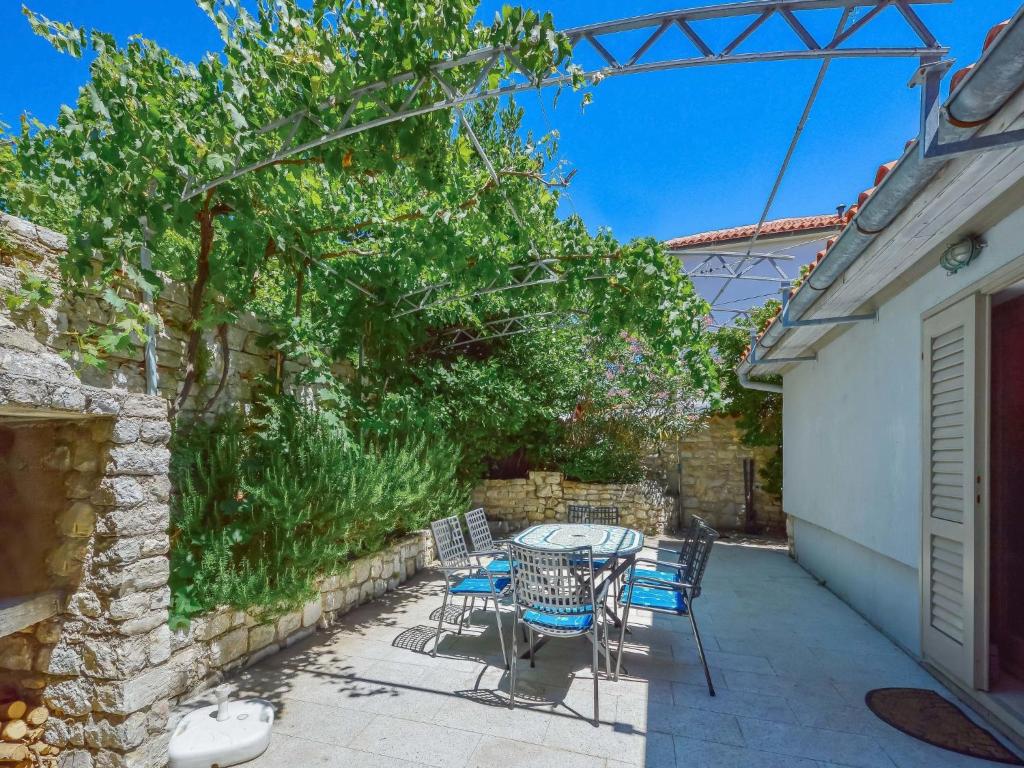 a patio with a table and chairs under a tree at Holiday Home Dubravka by Interhome in Osor