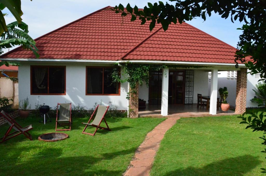 uma casa com telhado vermelho e cadeiras no quintal em Barazani Garden Villa em Moshi