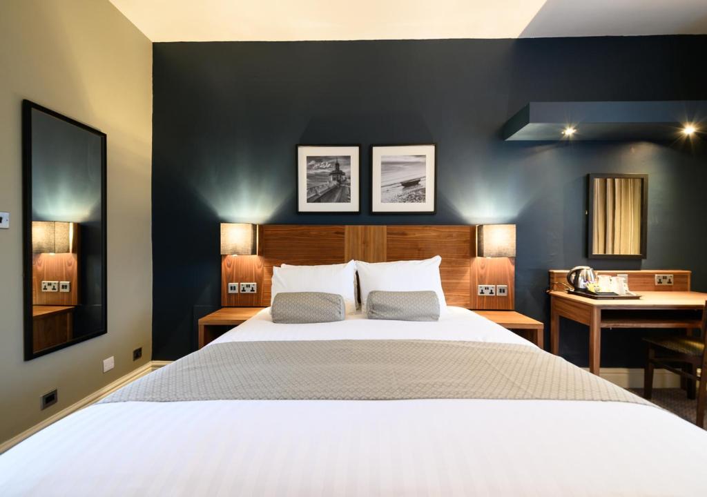 a bedroom with a large white bed and a desk at The County Hotel by Innkeeper's Collection in Lytham St Annes