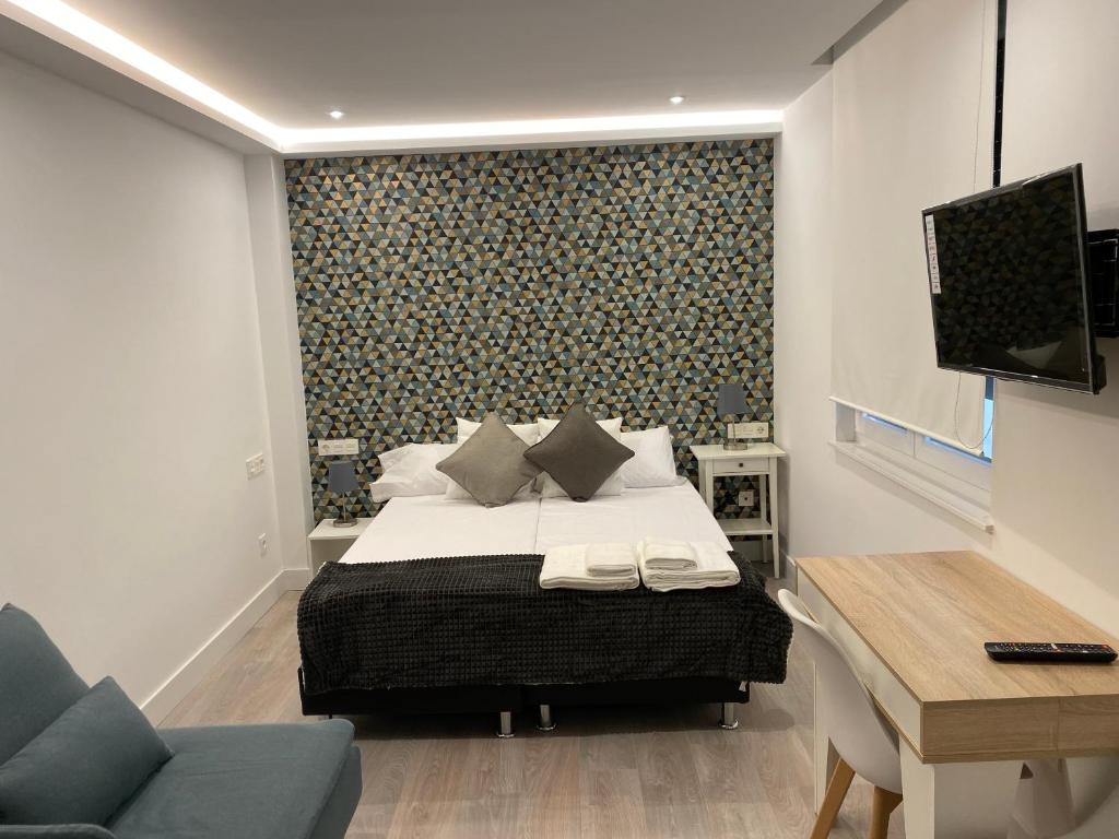 um quarto com uma cama, uma secretária e uma televisão em WILLMARK 2 em Salamanca