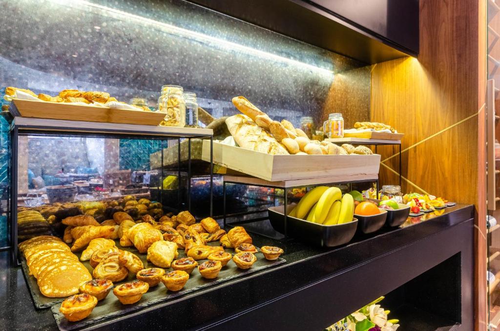 A lit breakfast display filled with pastries, breads, fruit, and jars.
