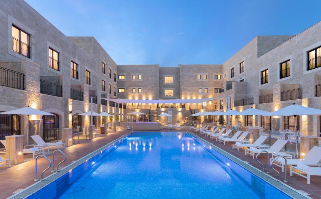 a pool with chairs and umbrellas in a hotel at Edmond Rosh Pina in Rosh Pinna