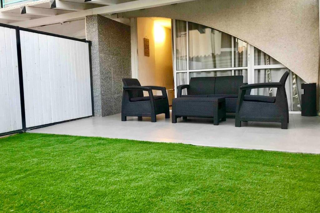 a patio with chairs and green grass in a building at Eilat Family Apartment Garden & Free Parking in Eilat