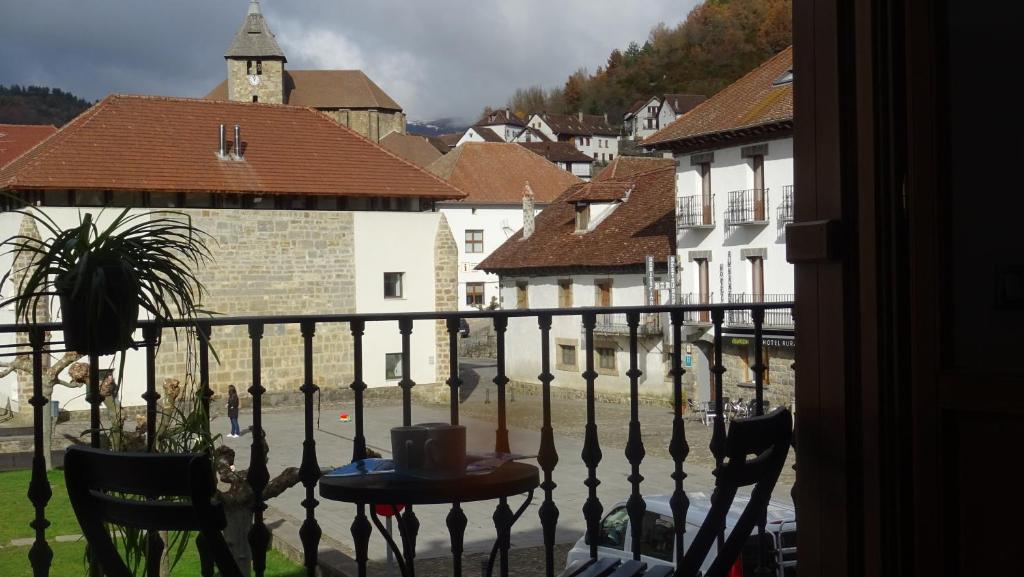 balcón con mesa, sillas y ciudad en Gaztanbide Apartamento rural, en Ochagavía