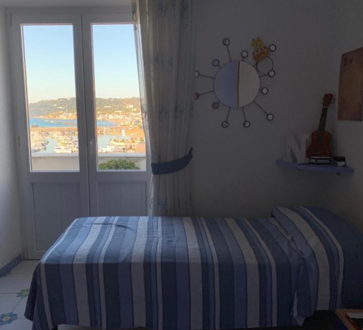 a bedroom with a bed and a large window at La Stanza sul Porto in Ischia