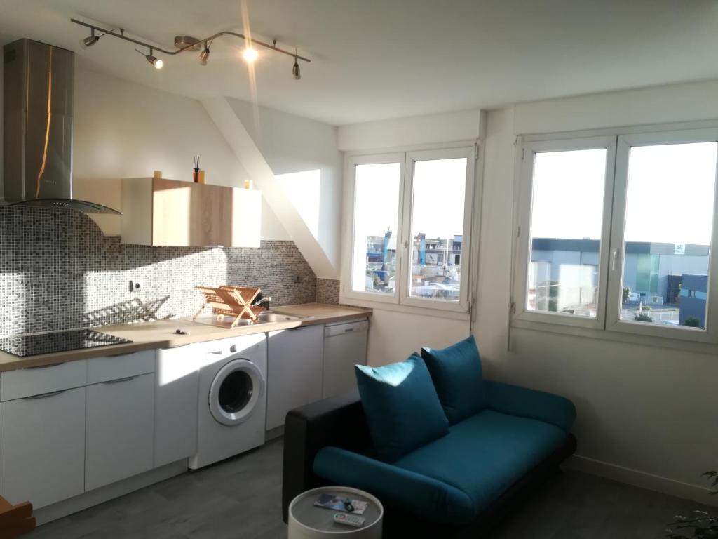 a kitchen with a washing machine and a blue chair at Le Sleepway Lorient in Lorient