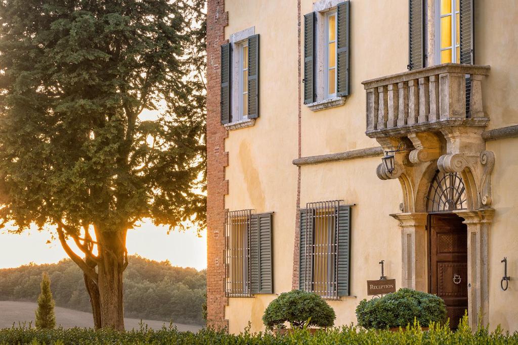 a building with a balcony and a tree at Villa Poggiano in Montepulciano