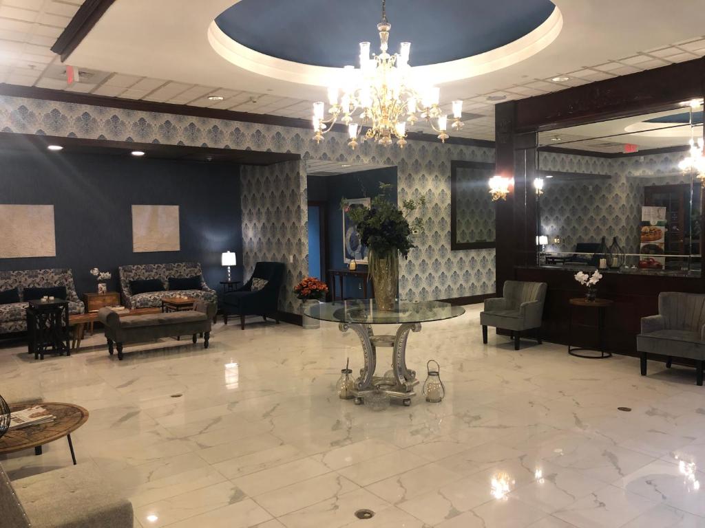 a lobby with a chandelier and tables and chairs at Clarion Hotel & Suites University-Shippensburg in Shippensburg
