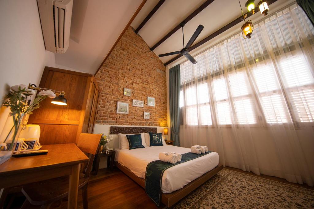 a bedroom with a bed and a desk and a window at Sweet Cili Boutique Hotel in George Town