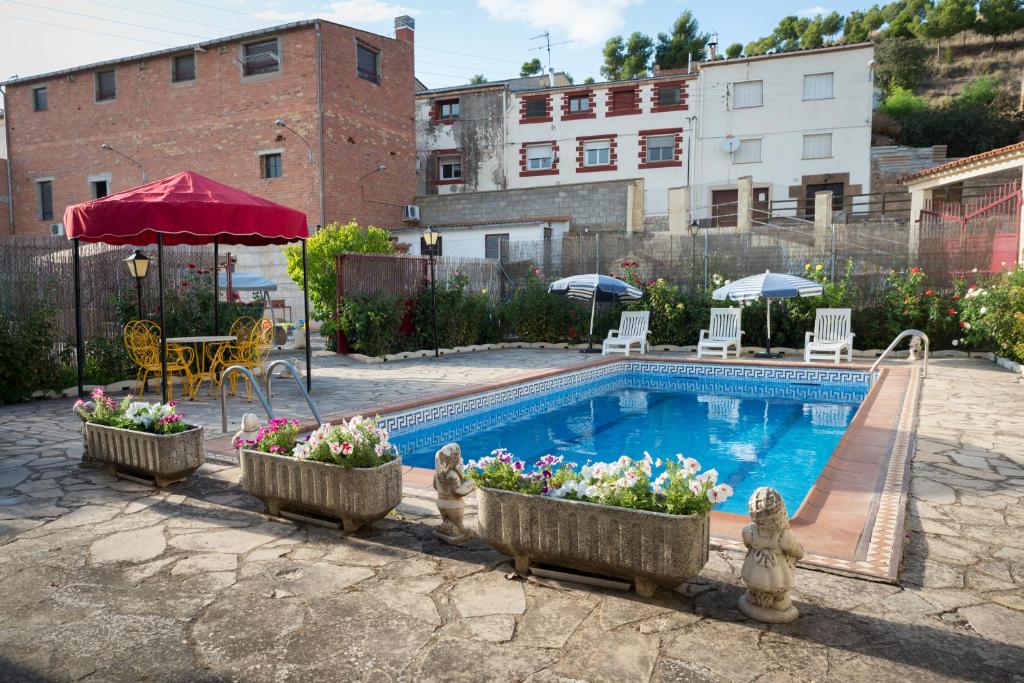 a swimming pool with flowers in containers next to a building at Cal Carreró in Claravalls