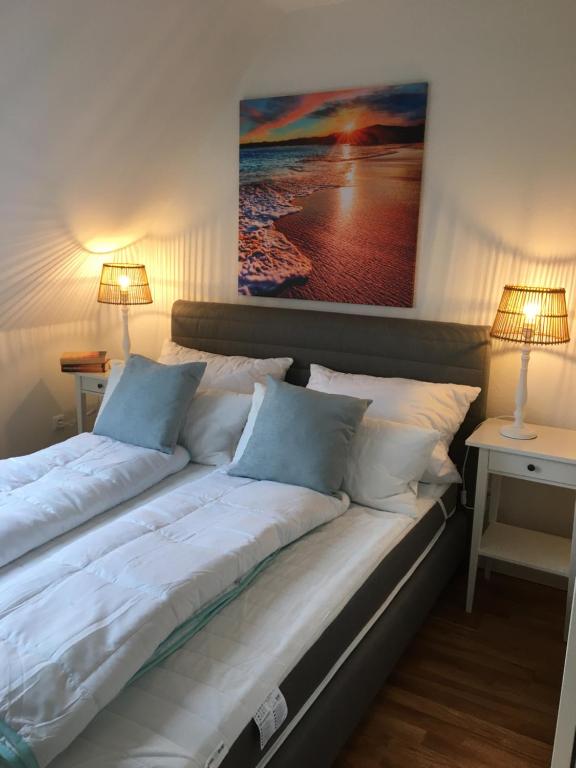 een groot bed met witte lakens en blauwe kussens bij Fewo Schröder - BUDE 63a - mit Strandkorb am Meer in Westerdeichstrich