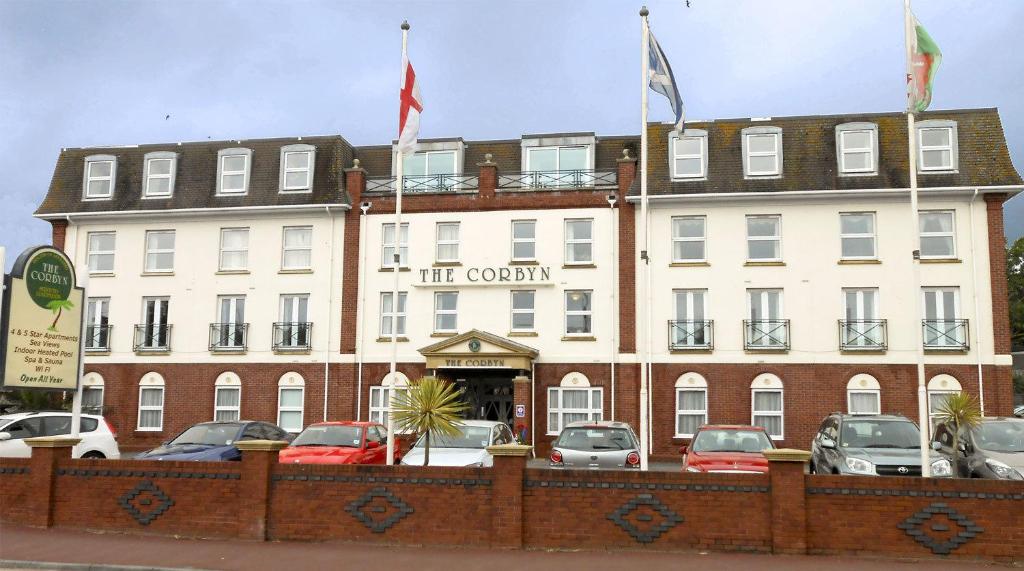 ein großes weißes Gebäude mit Flaggen darüber in der Unterkunft The Corbyn Apartments in Torquay