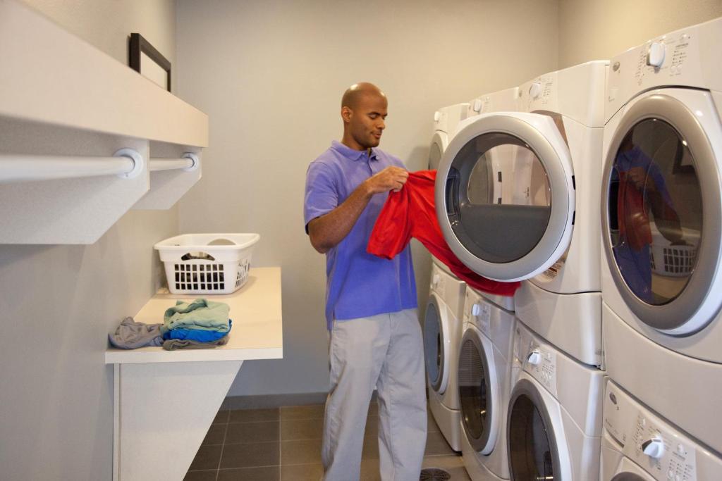 Een man stopt een rode handdoek in een wasmachine. bij Staybridge Suites - Scottsdale - Talking Stick, an IHG Hotel in Scottsdale