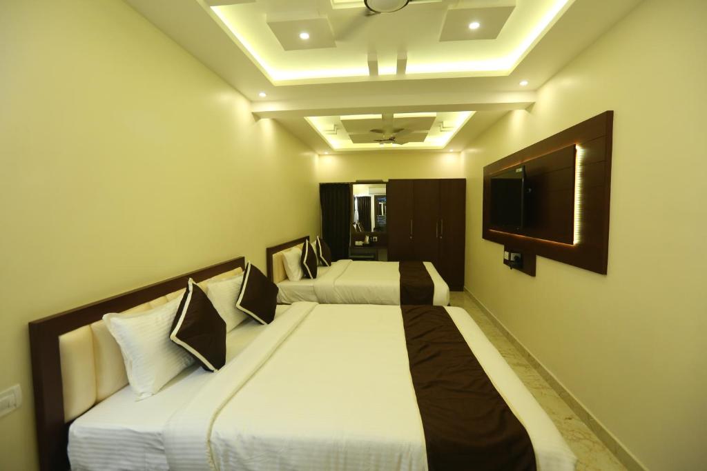 a hotel room with two beds and two lamps at Al Noor Palace Business Class Hotel in Chennai