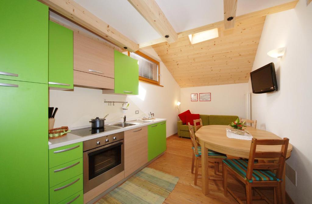 une cuisine avec des placards verts et une table en bois dans l'établissement Casa Seler - Appartamento verde, à Predazzo