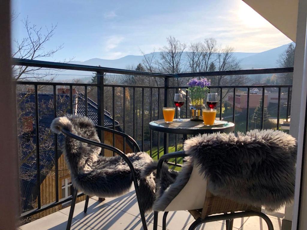 uma varanda com uma mesa e cadeiras com vista em Apartamenty Villa Incognito em Szklarska Poręba