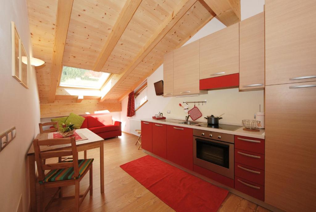 プレダッツォにあるCasa Seler - Appartamento rossoの赤いキャビネットとテーブル付きのキッチンが備わります。